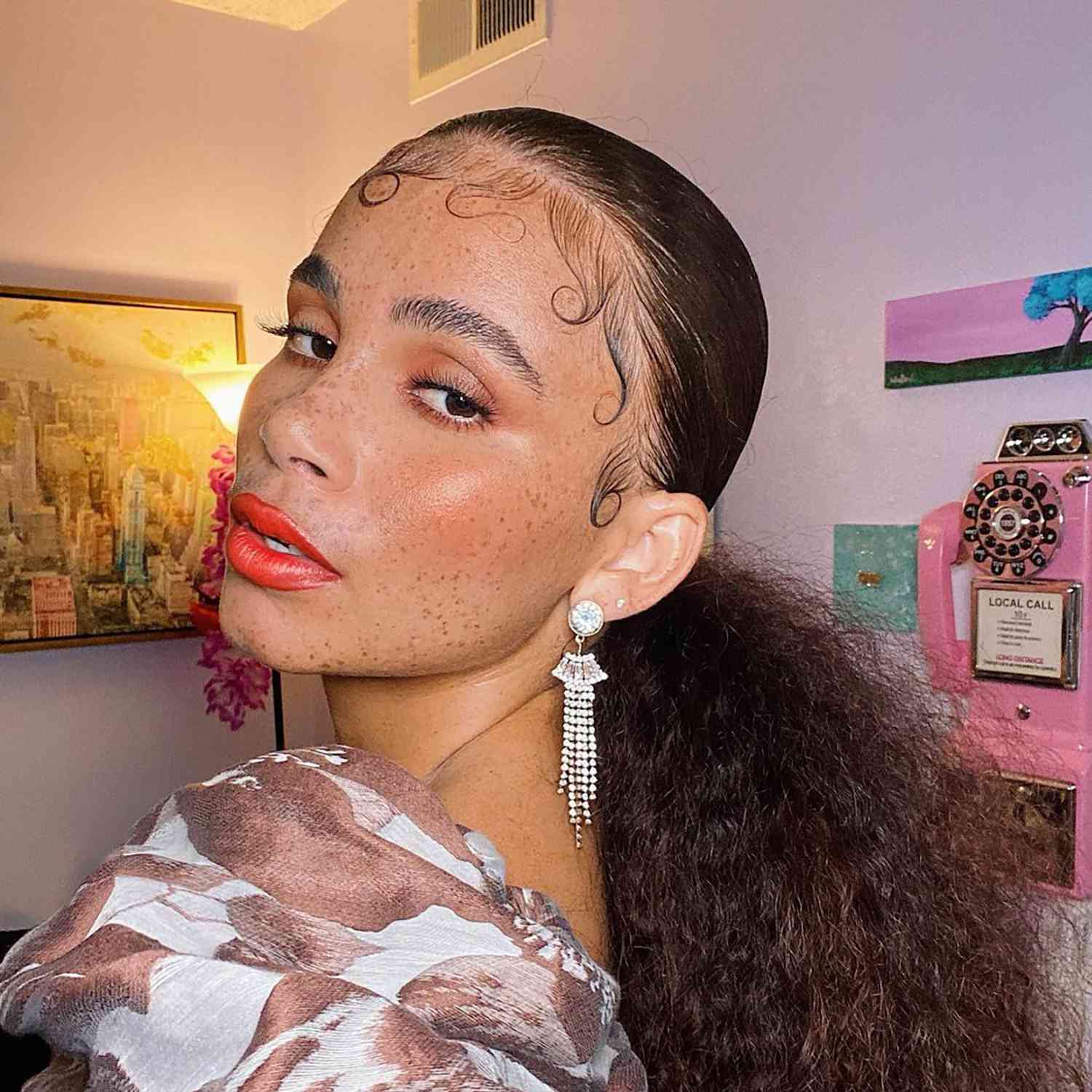 Close up of a woman with bold lipstick, a smooth pony tail, and laid baby hair