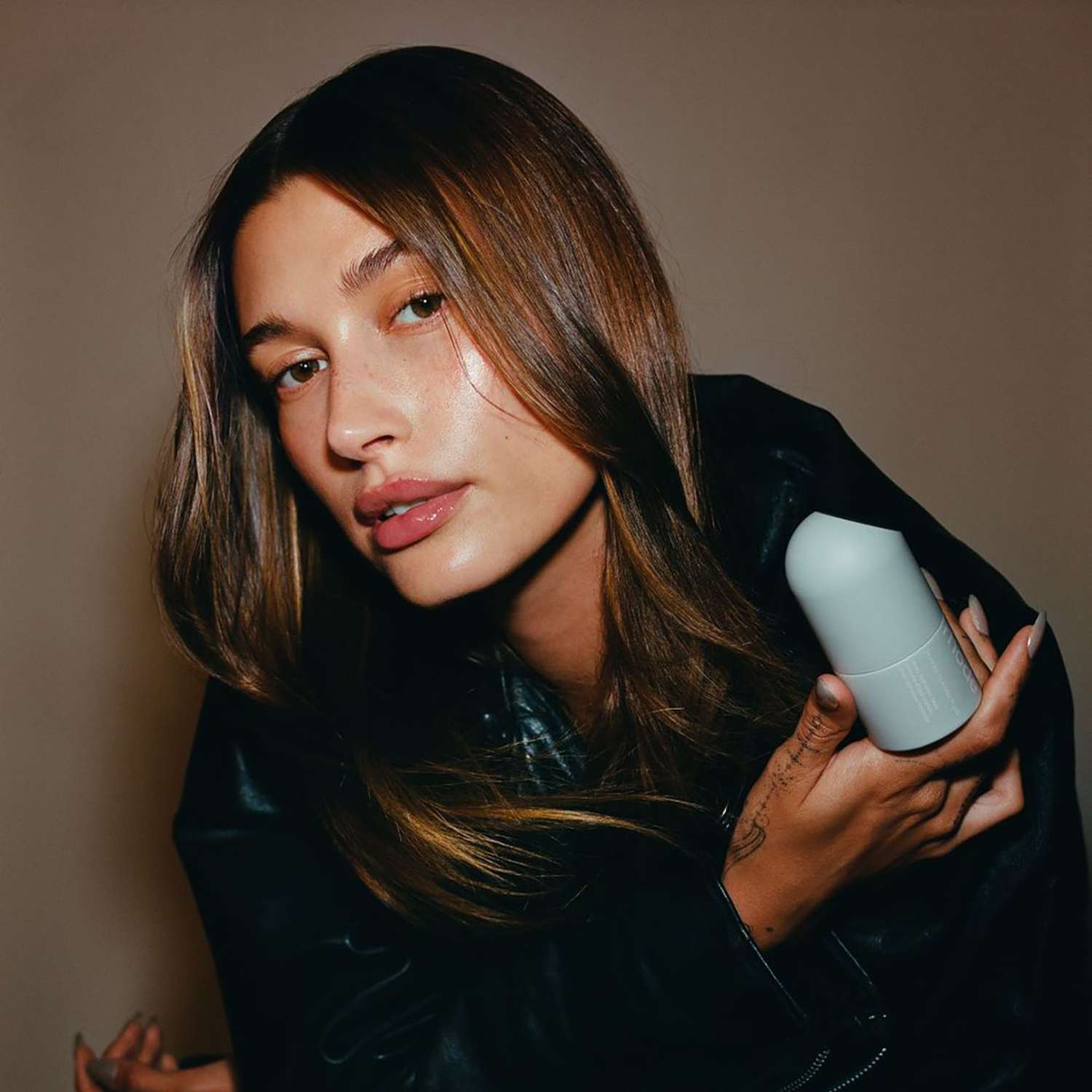 Close up of Hailey Bieber holding a Rhode Skincare product