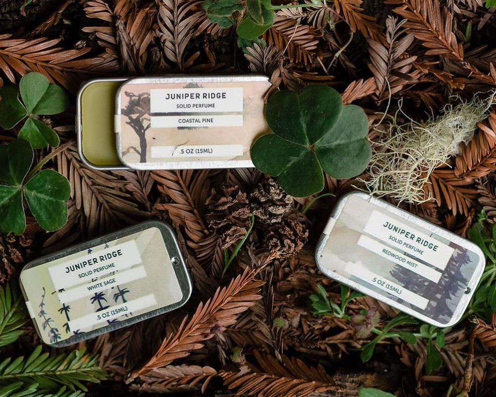 Juniper Ridge solid cologne tins on leafy ground background