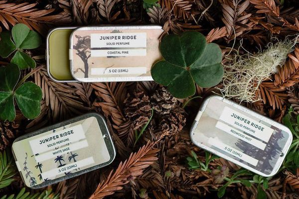 Juniper Ridge solid cologne tins on leafy ground background