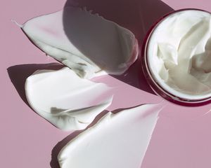 Three swatches of moisturizer beside a jar