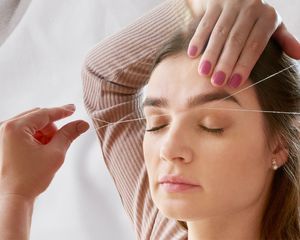 Women threading eyebrows 