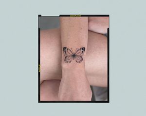 A forearm with a minimalistic butterfly tattoo