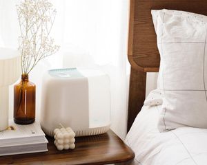 Humidifier on a nightstand, beside a bed