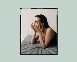 woman rubbing eyes on a bed