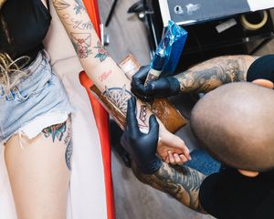 Tattoo artist giving customer tattoo on arm