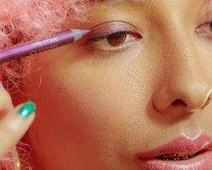 girl putting on eyeliner in pink aesthetic