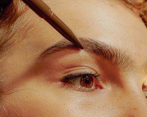 Woman penciling in her brows.