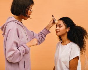 young woman getting makeup done in studio