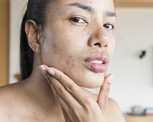 Woman looking at herself while holding her chin in her hand.