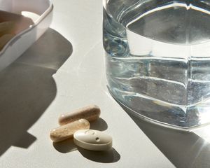 Pills on a table with a glass of water