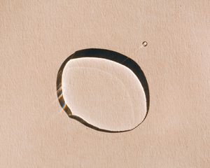 droplet of skincare oil on tan background