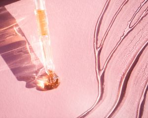 Swatches of a light yellow oil on a pink background.