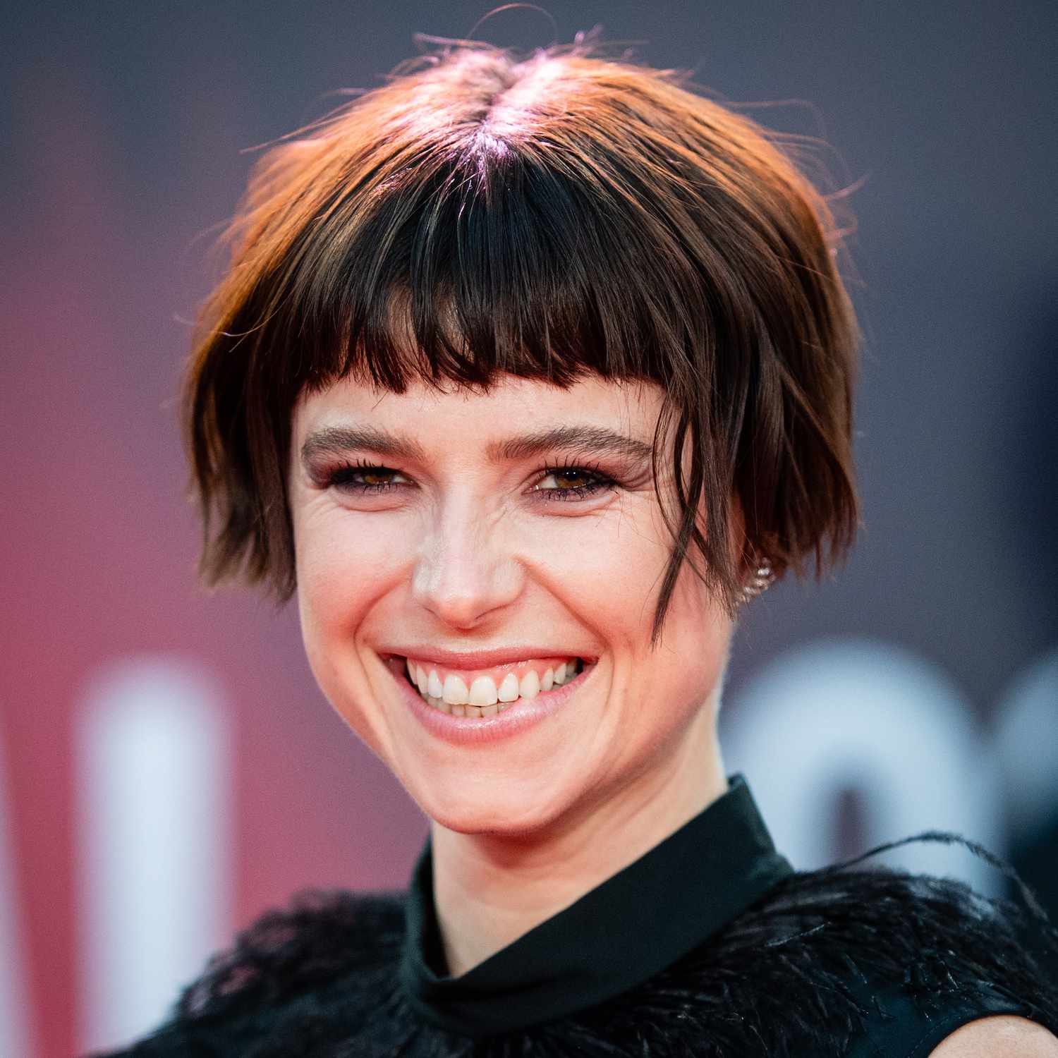 Jessie Buckley wears a micro bob hairstyle with baby bangs