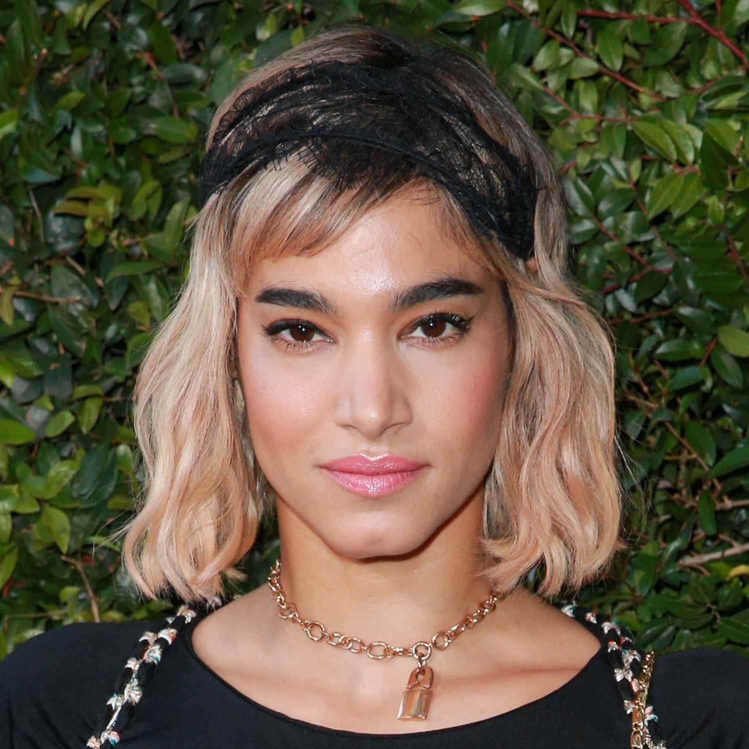 Sofia Boutella wears a wavy long bob hairstyle with side-swept baby bangs and black lace headband