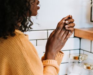 woman washing hands in tiled bathroom
