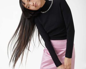 Model wearing embellished turtleneck and pink mini skirt.
