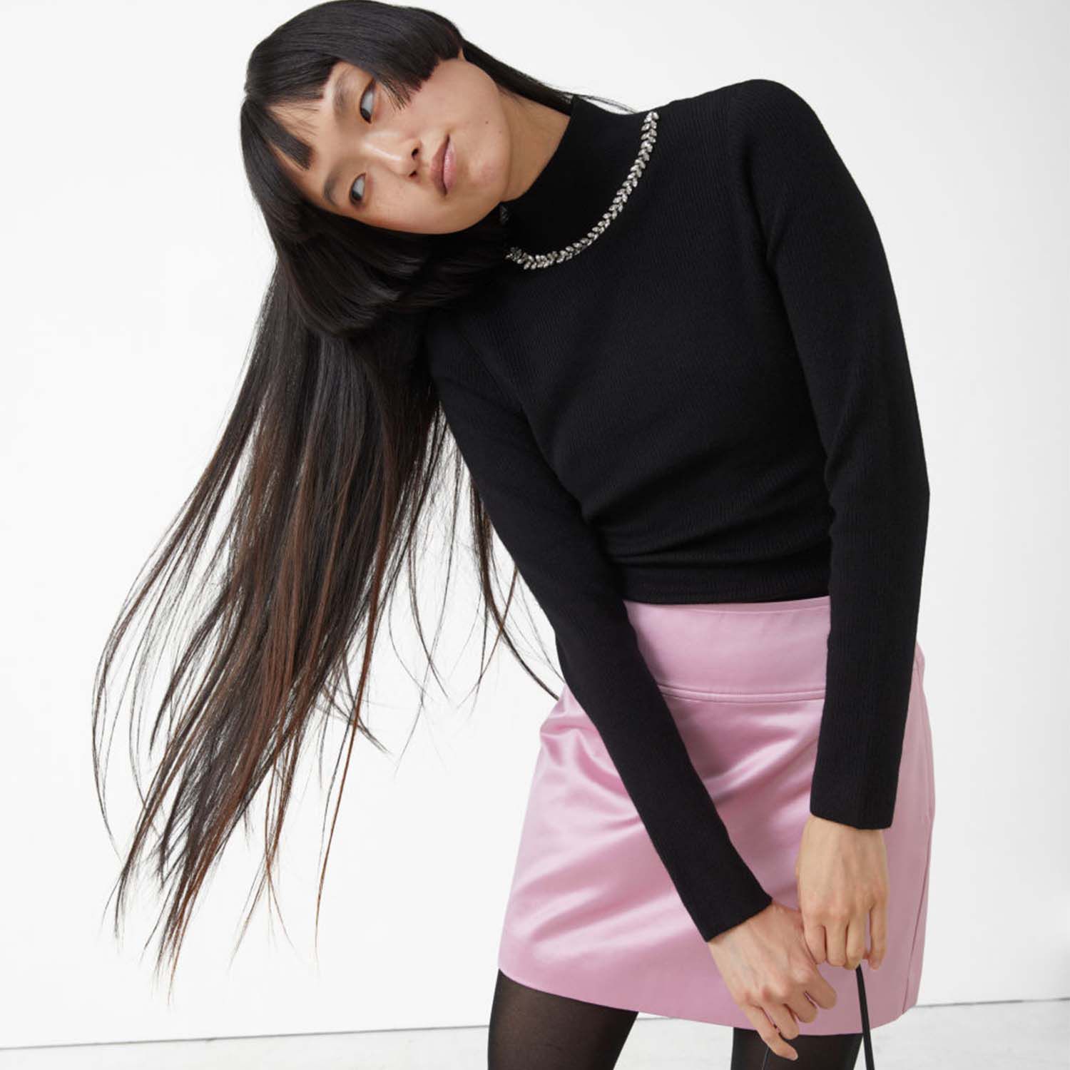 Model wearing embellished turtleneck and pink mini skirt.