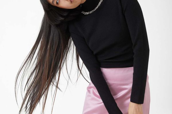 Model wearing embellished turtleneck and pink mini skirt.