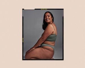 Woman smiles over her shoulder, hands on her knees while sitting on the ground