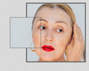 Up close of a mature woman with her hair pulled back, hand at her temple.