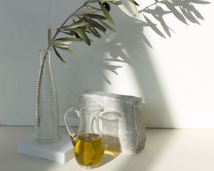 Olive oil in a pitcher and an olive branch in a vase