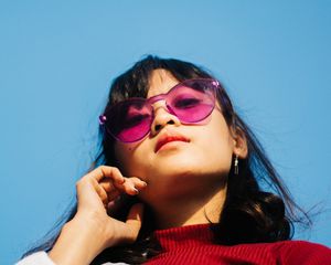 woman in sunglasses outside touching her face