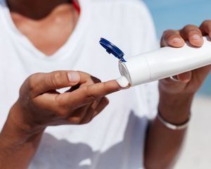 woman squeezing sunscreen onto finger