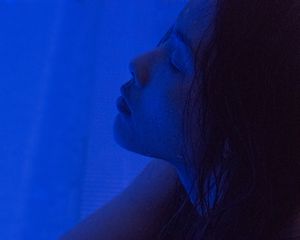 Side profile of woman's face in vibrant blue light