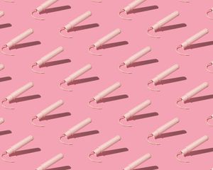 Tampons with pale pink applicators on pink background