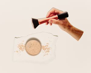 hand dipping brush into powdered makeup
