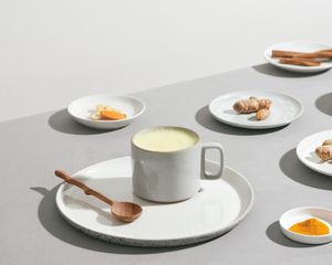 Milk, turmeric, ginger, and cinnamon on a gray table.