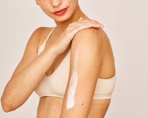 Woman rubbing lotion on her arm