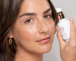 Model wearing and holding the True Botanicals Everyday Skin Tint 