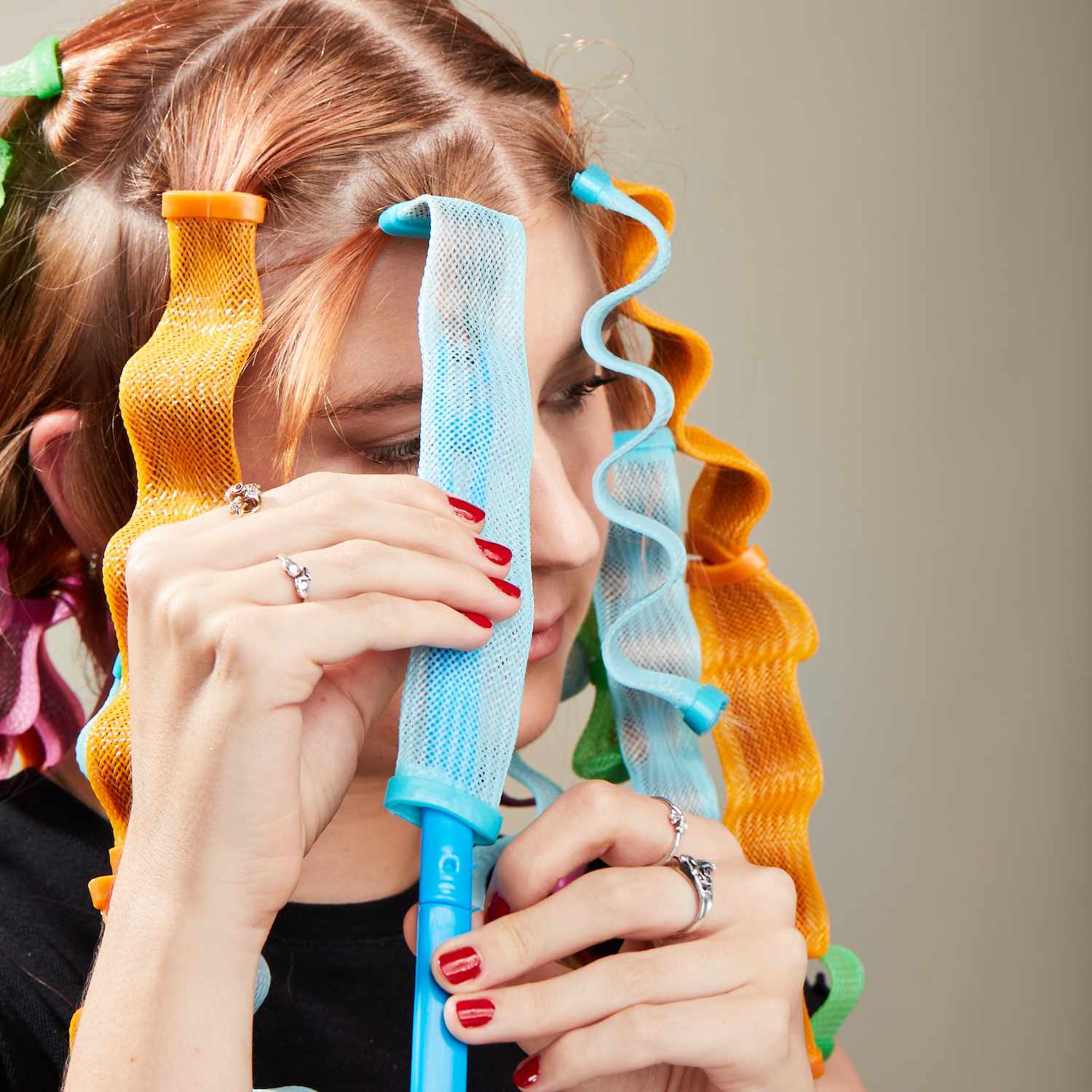 Byrdie editor Bella Cacciatore pulling a section of her hair through a waveformer with a hook