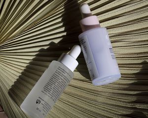 Two bottles of hyaluronic acid on a palm leaf