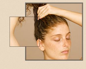 Close up of a woman's hairline as she pulls her hair into a ponytail.
