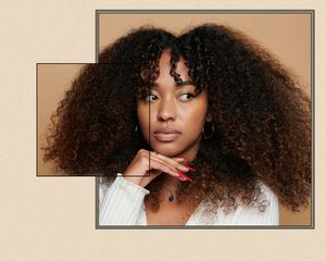 Woman with curly brown hair looks to the side, with her hand on her chin.