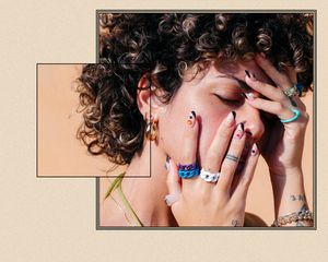 Up close of a woman's manicured hands on her face.