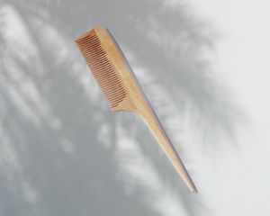 Japanese wooden beard comb with tail on gray palm shadow background