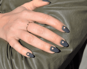 Charcoal gray nails with a nude dot on each.