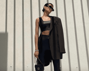 Woman wearing faux leather leggings and crop top, blazer, sunglasses, and purse