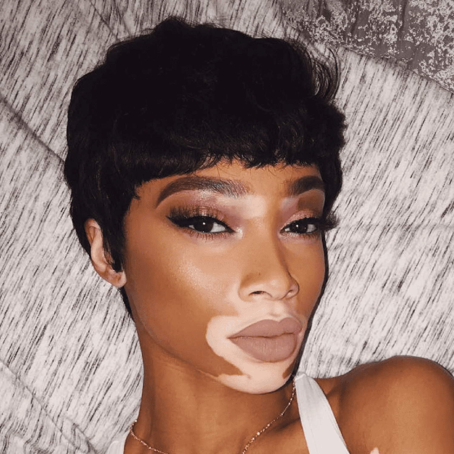 Winnie Harlow with a pixie haircut and baby bangs