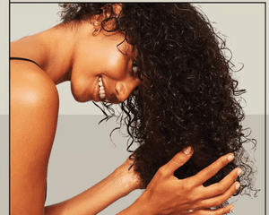 black woman holding her head upside down and scrunching her curls